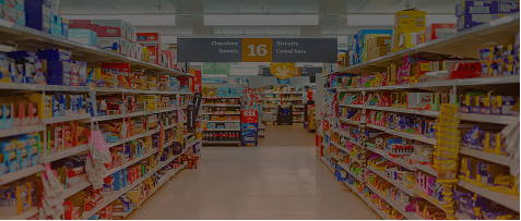 Grocery store aisle stocked with products on shelves on both sides and an aisle 16 sign above the walkway.